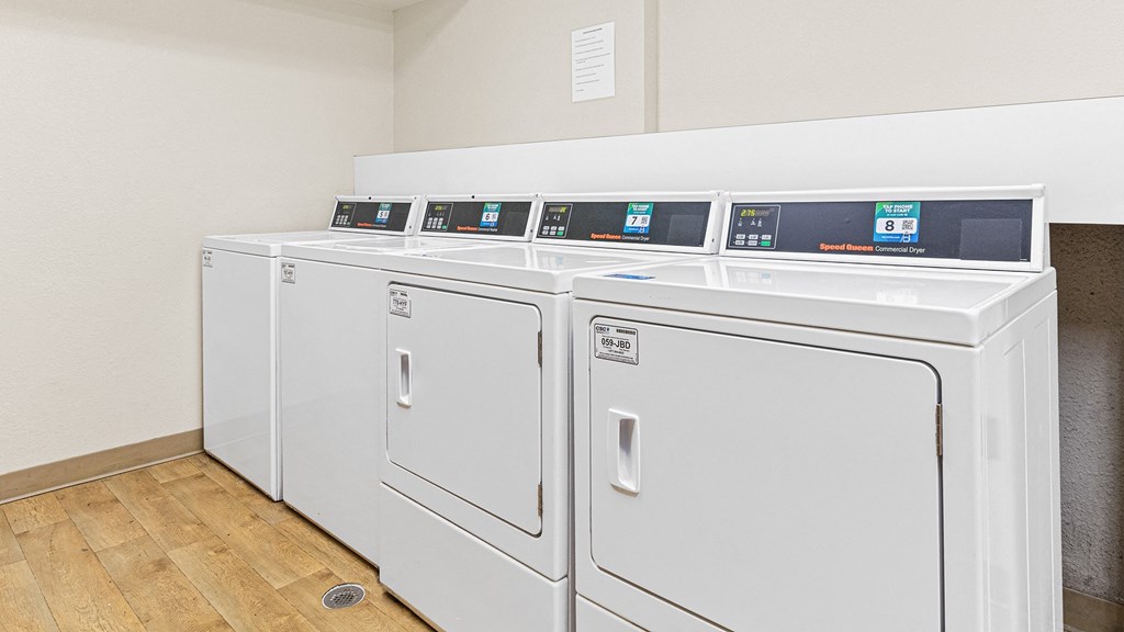 a row of washers and dryers in a laundry room