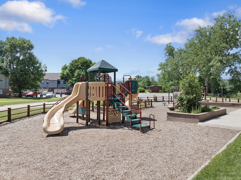 A playground with a slide, swings, and a green roofed structure.