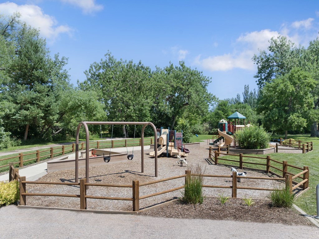 A playground with a swing set and a wooden fence.