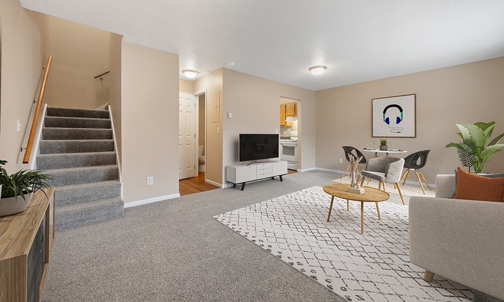 A living room with a grey carpet and a white rug with a black and white pattern.