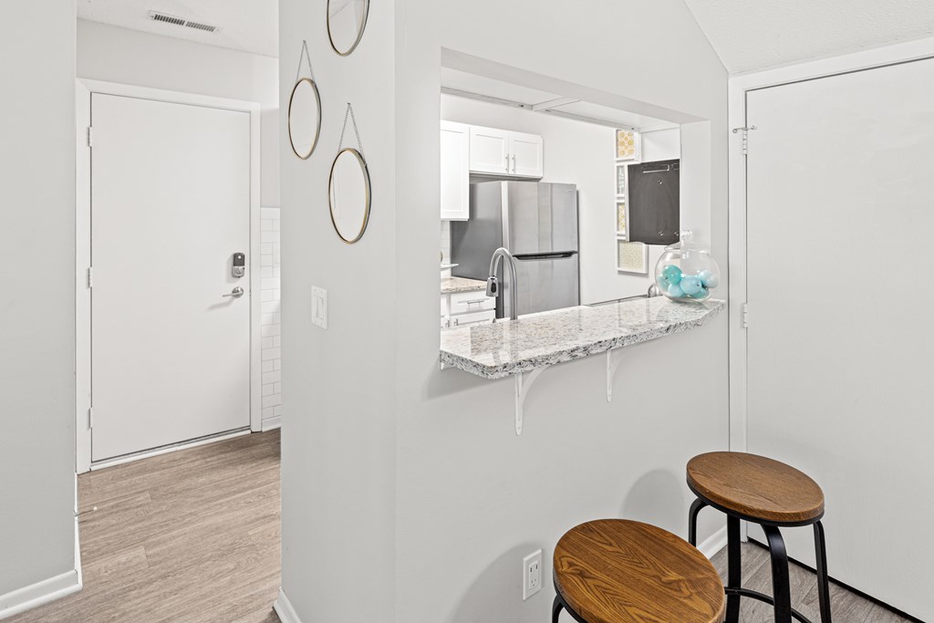 A kitchen with a bar stool in front of a counter.