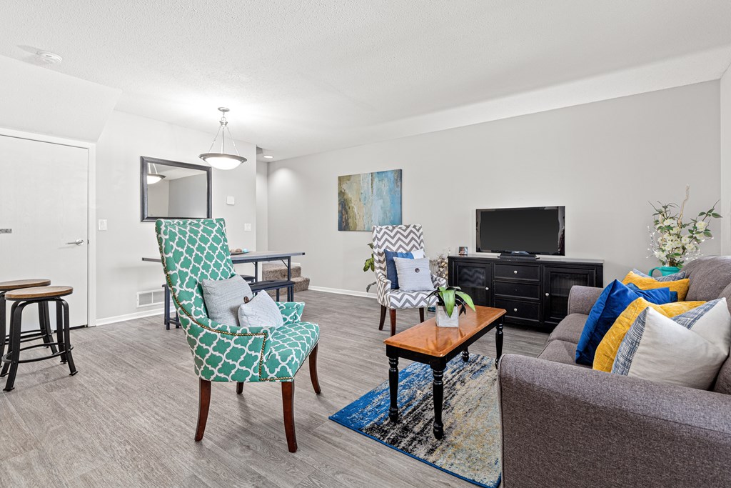 A living room with a grey couch, a green and white patterned chair, and a wooden coffee table.