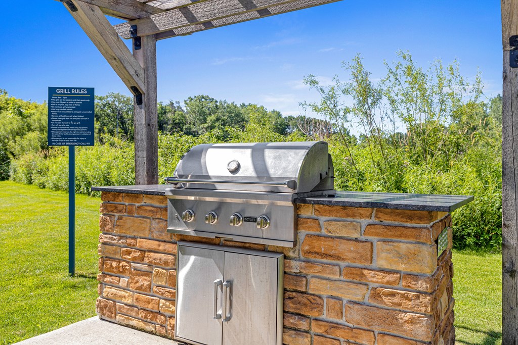 A brick oven is under a wooden pergola.