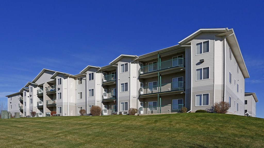 an apartment building on a hill with a green lawn