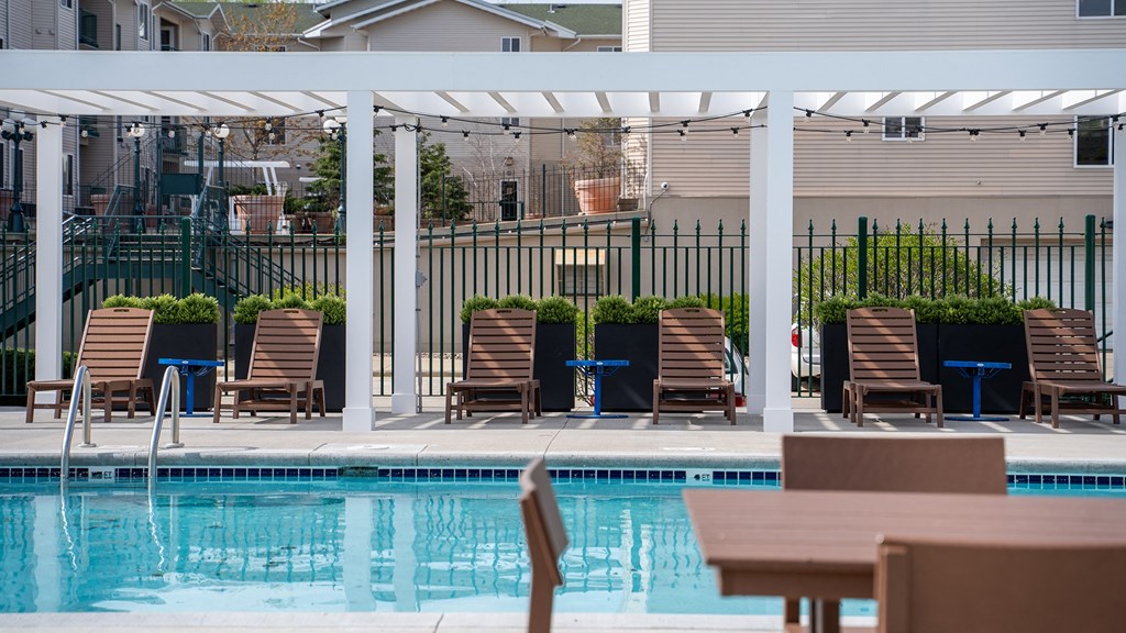 a swimming pool with chairs and a table under a canopy