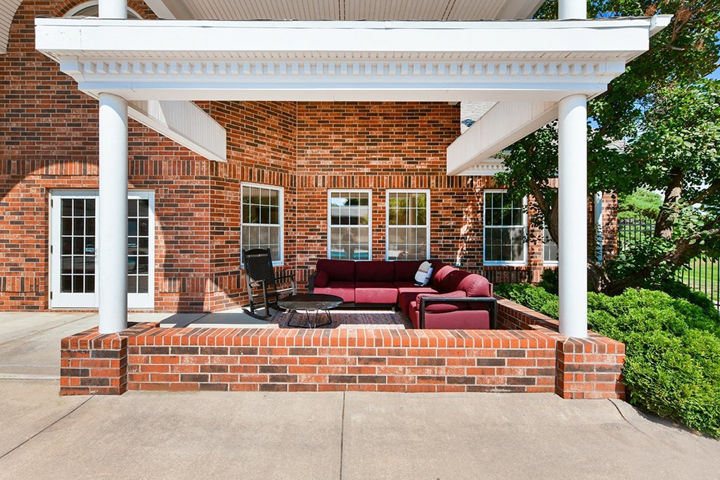 A red couch is on a patio with a white roof at The Donovan Apartment Homes, Nebraska