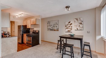 Carpeted living room off of kitchen with three person dining table against wall - Photo Gallery 6