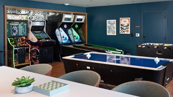 a gaming room with arcade games and tables at The Bosk Apartment Homes, Woodbury, MN