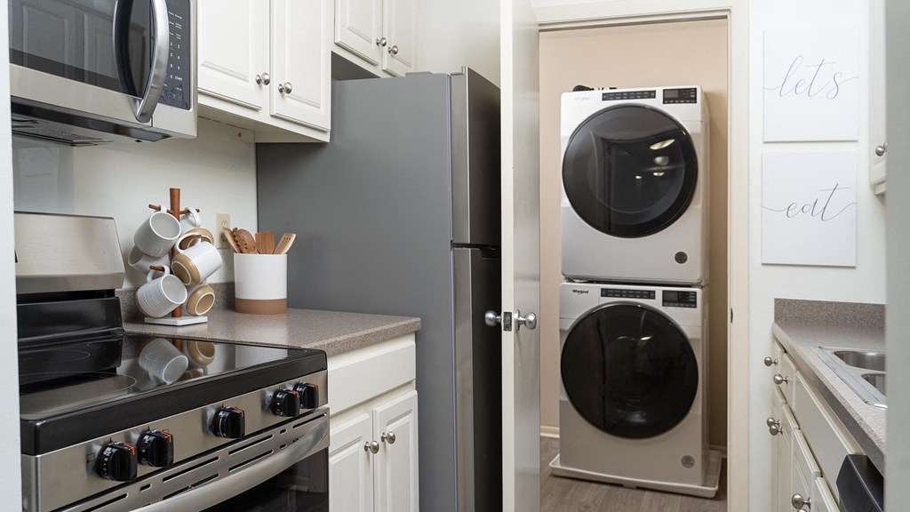 A modern kitchen with a stove, microwave, and a washing machine. A modern kitchen with a stove, microwave, and a washing machine at The Bosk Apartment Homes, Woodbury, MN