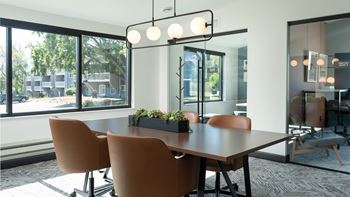 a conference room with a large window and a table with chairs at The Bosk Apartment Homes, Minnesota 55125