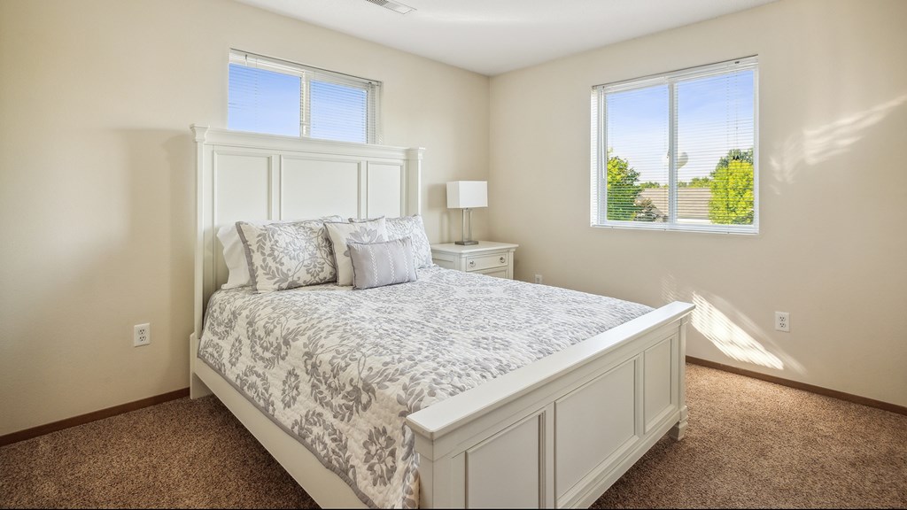 A bedroom with a large bed and a window overlooking a green landscape.