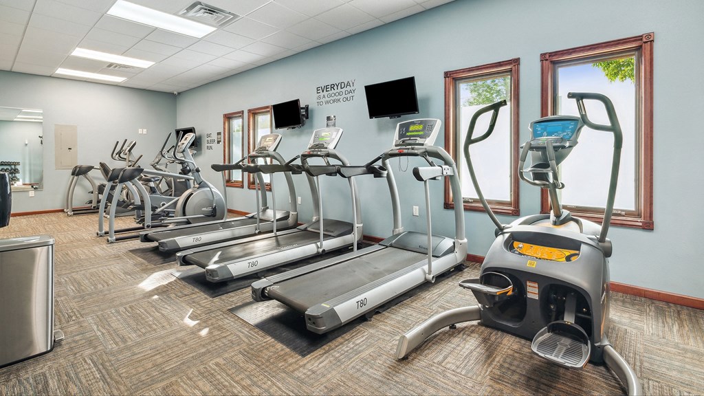 A gym with treadmills, elliptical machines, and other exercise equipment.