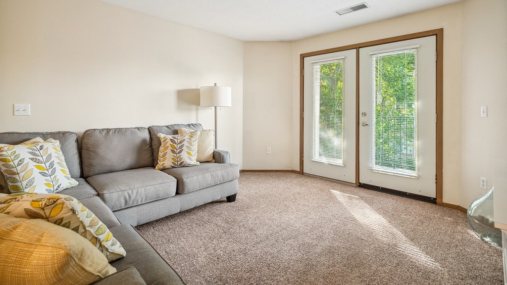 A living room with a grey couch and a lamp.