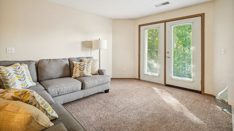 A living room with a grey couch and a lamp.