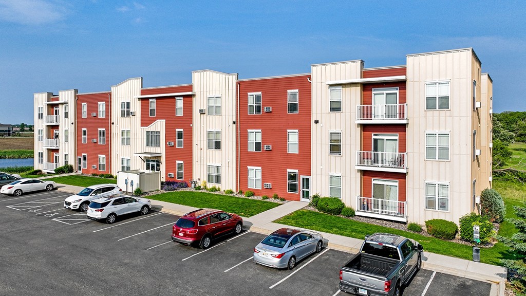 an exterior view of an apartment building with cars parked in a parking lot