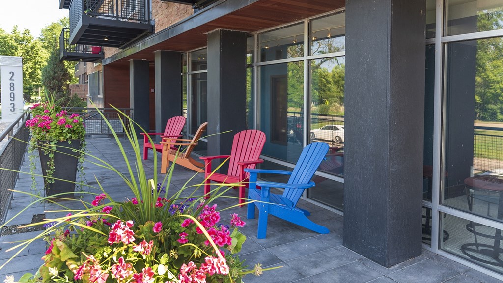 a patio with red and blue chairs and pink and white flowers