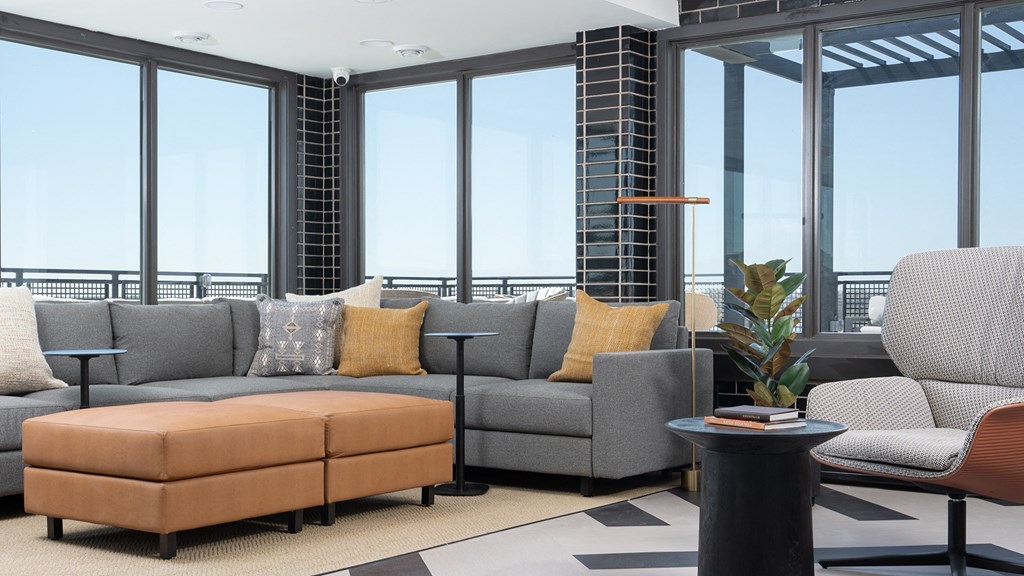 a living room with a gray couch and a table and windows