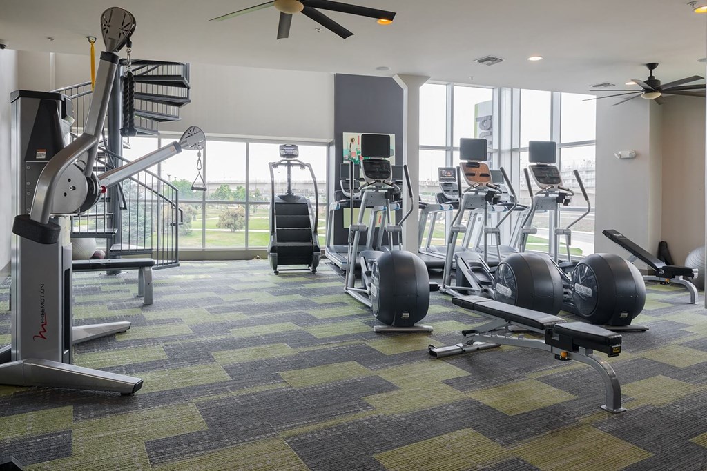 a gym with treadmills and other exercise equipment with a large window in the background