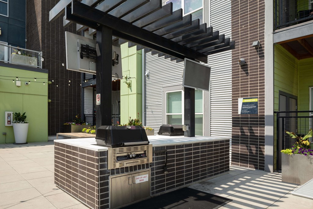 Community grills shaded by a pergola perfect for a summer cookout.