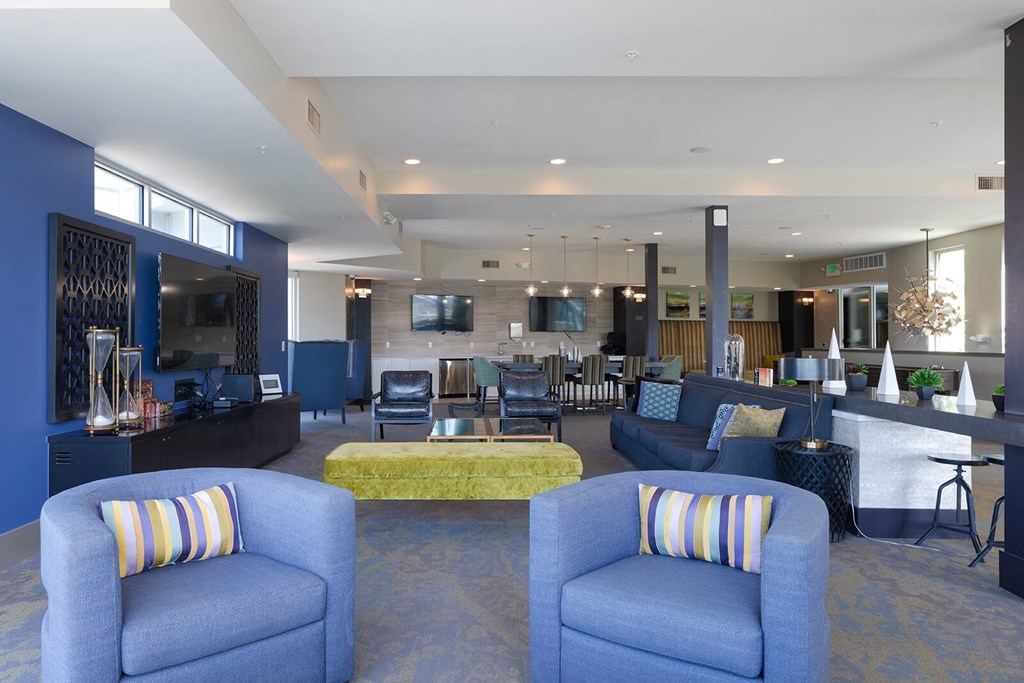 a lobby with blue couches and chairs with a yellow couch in the middle of the room