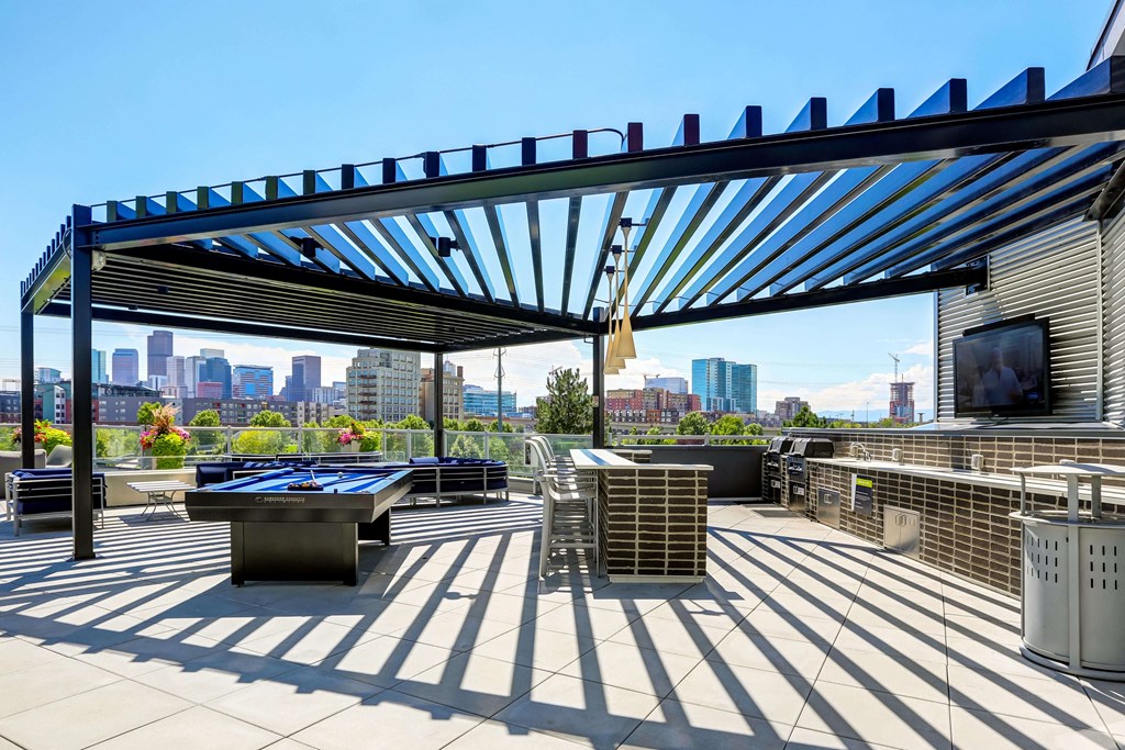 Sky deck at Westend Apartments featuring a full grilling station, billiards table, and island seating covered by a pergola.