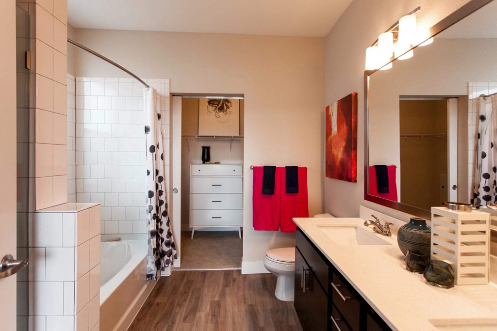 Bright and stylish bathroom with a full shower, double vanity sink, and quartz countertops. Bathroom leads into walk in closet.