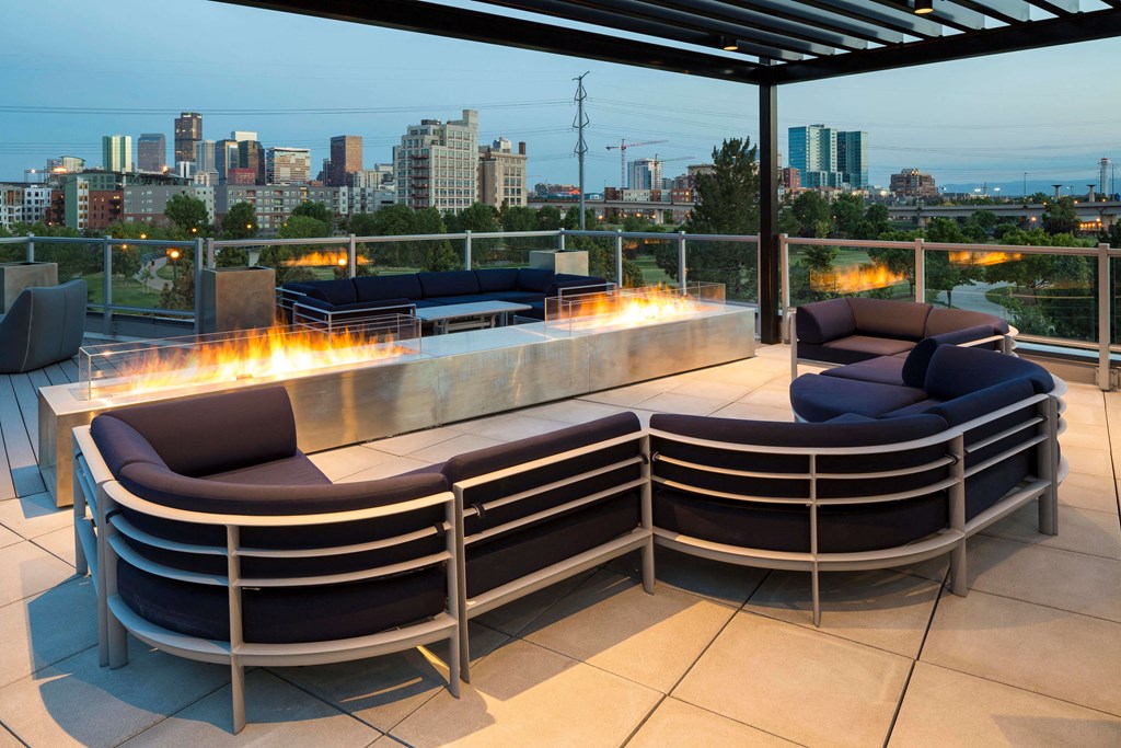 The stylish rooftop features a large outdoor fireplace, comfortable seating, and a pergola all looking out onto stunning skyline views.