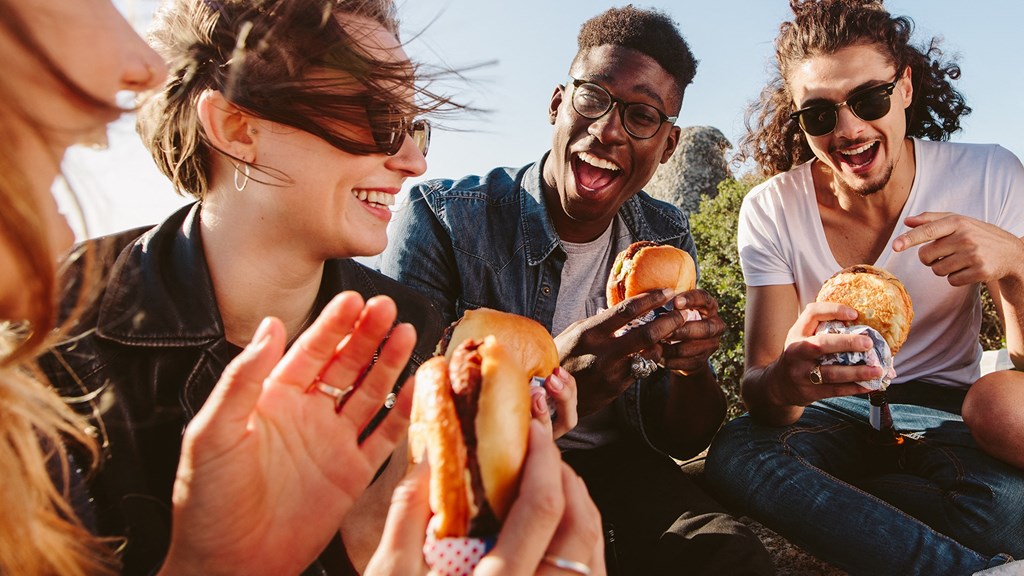 a group of people eating hot dogs    and laughing