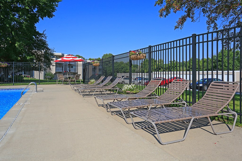 Pool side lounge chairs against surrounding fence