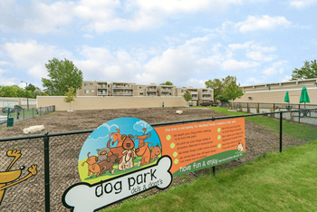 Gated dog park with woodchips and sign on surrounding fence at The Bosk Apartment Homes, Woodbury, MN, 55125