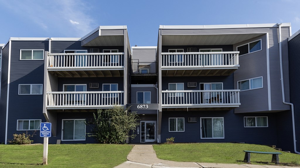 a blue apartment building with balconies and a lawn