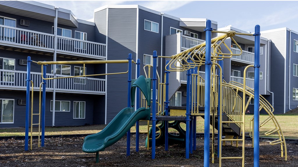 a playground with a slide and monkey bars in front of a building