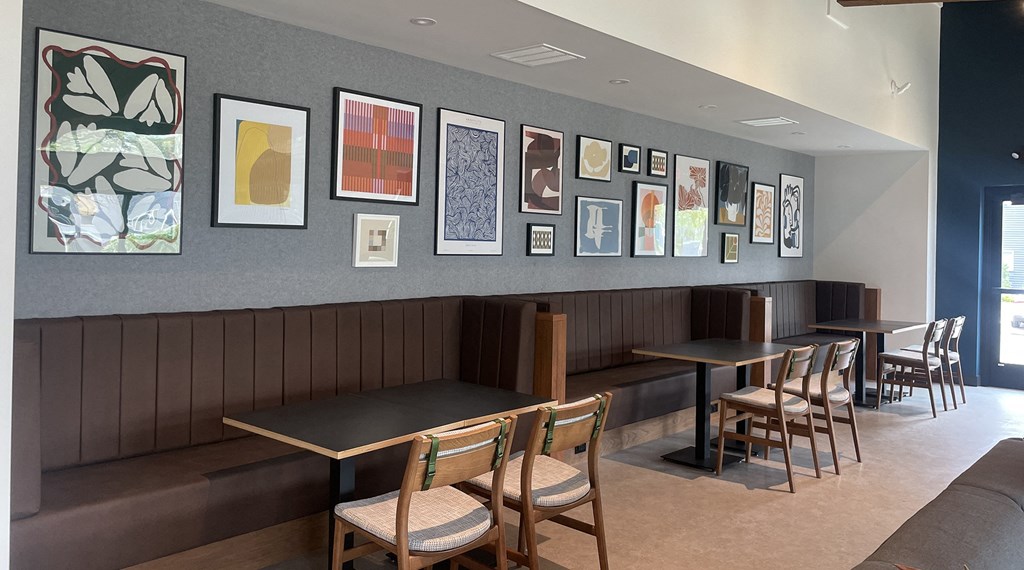 a seating area with tables and chairs and pictures on the wall