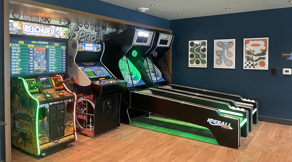 a display of arcade games in a room with a wall of graffiti