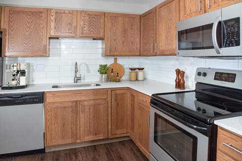 a kitchen with wooden cabinets and black appliances and white tiles