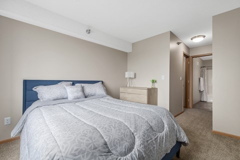 A bedroom with a large bed and a carpeted floor.