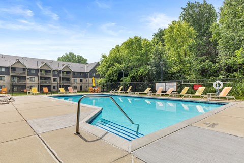 A large swimming pool with a diving board and lounge chairs.