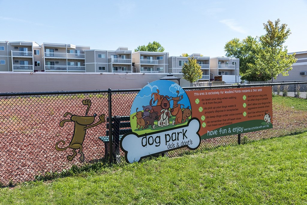 a dog park sign on a fence in front of an apartment building