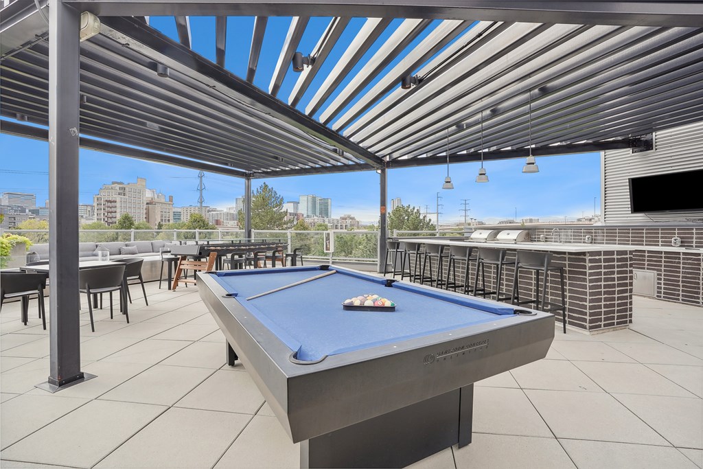 A pool table is in the middle of a patio with a metal roof.