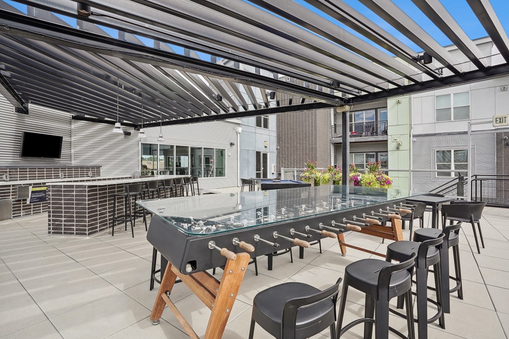 A glass table with chairs under a metal roof.
