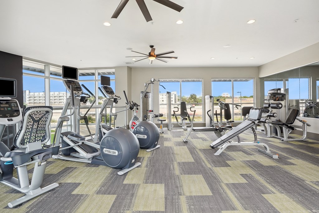 A spacious gym with a variety of equipment and a ceiling fan.