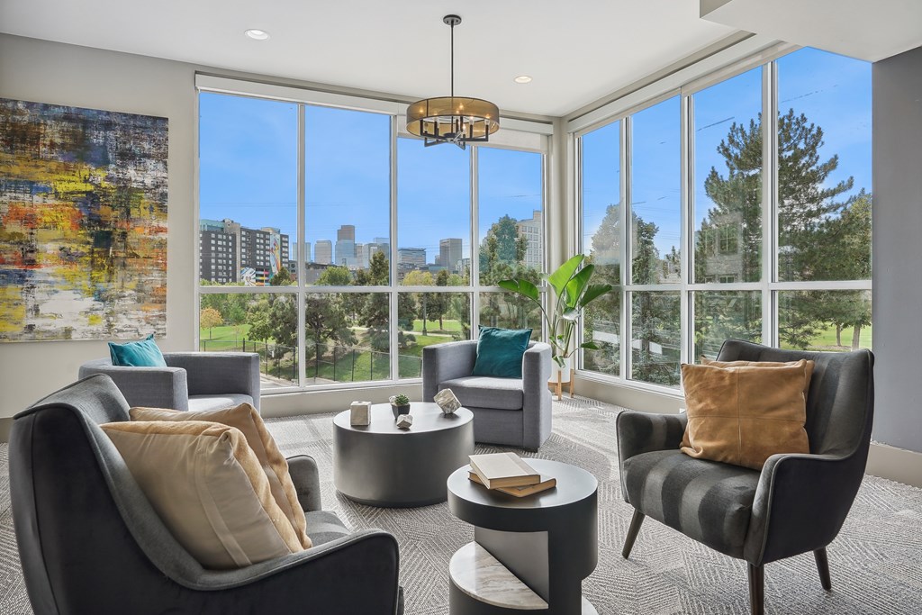 A living room with grey chairs and a large window overlooking a city.