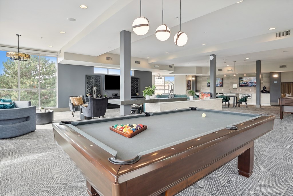 A pool table in a room with a TV and a bar.
