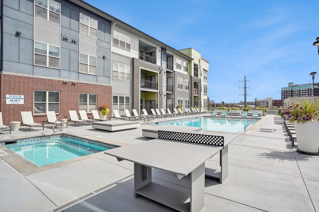 A pool area with a table and chairs in front of a building.