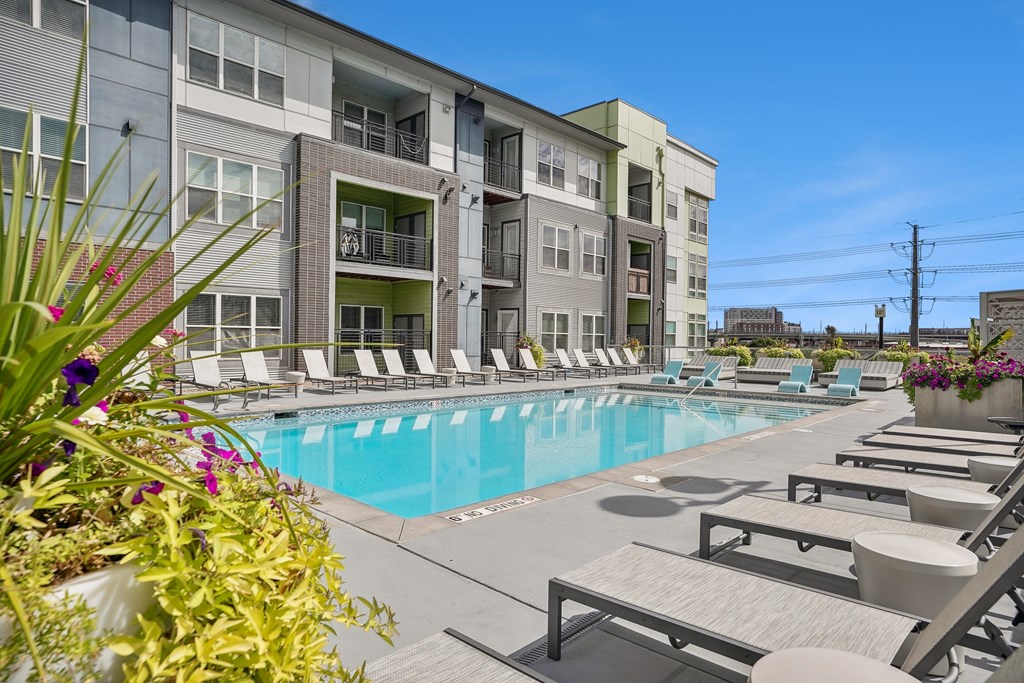 A pool area with sun loungers and a building in the background.