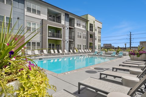 A pool area with sun loungers and a building in the background.
