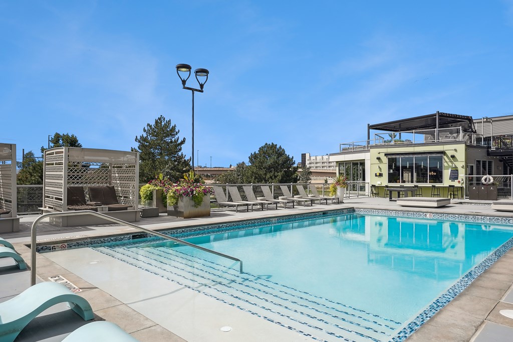 A large swimming pool with lounge chairs and a building in the background.