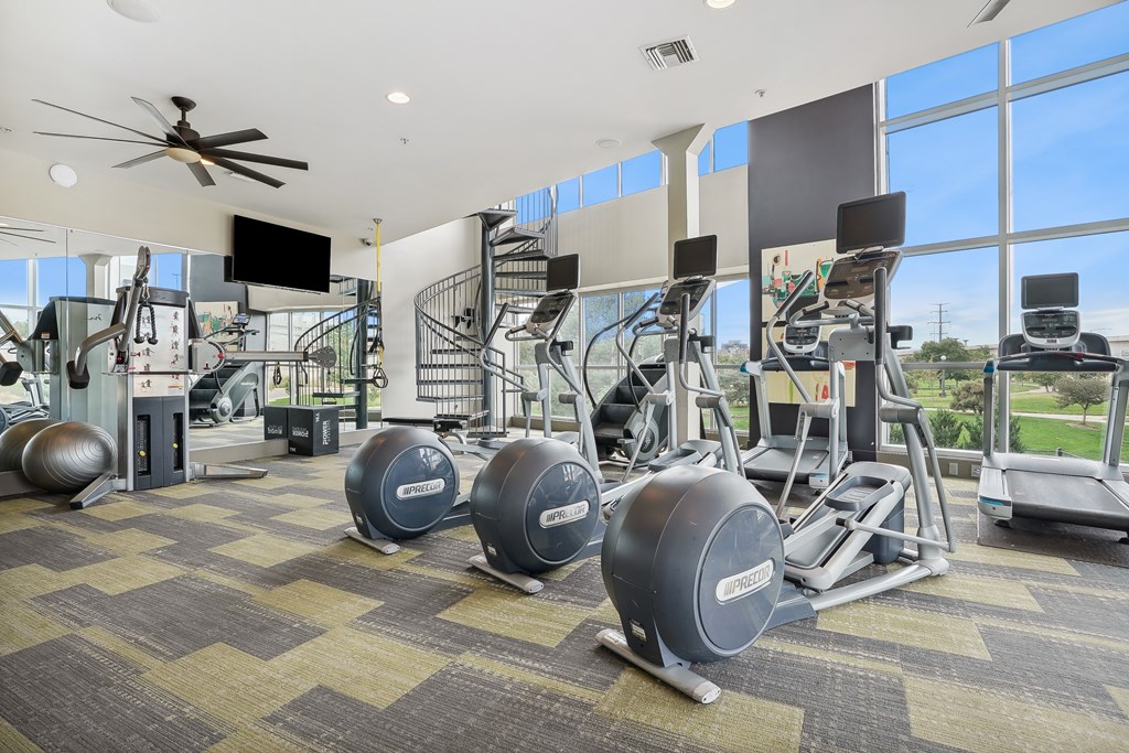 A gym with a variety of equipment including treadmills, weights, and exercise machines.