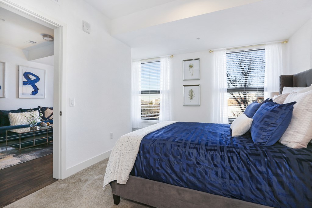 a bedroom with a blue bed and two windows