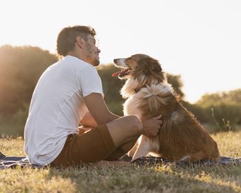 a man sitting on the grass with his dog